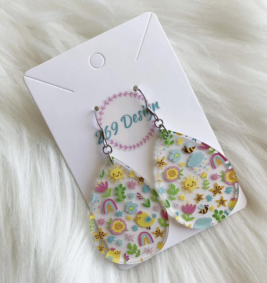 teardrop shaped clear acrylic earrings printed with spring things like flowers bees rainbows green leaves and baby chicks